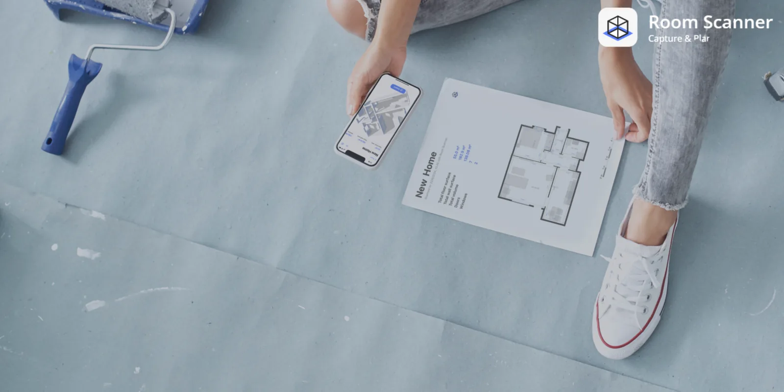 Room Scanner displayed on a phone beside a printed floor plan during a renovation